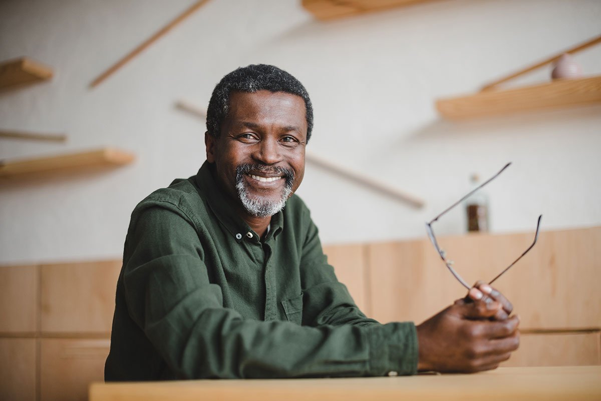 Smiling Black man holding eyeglasses