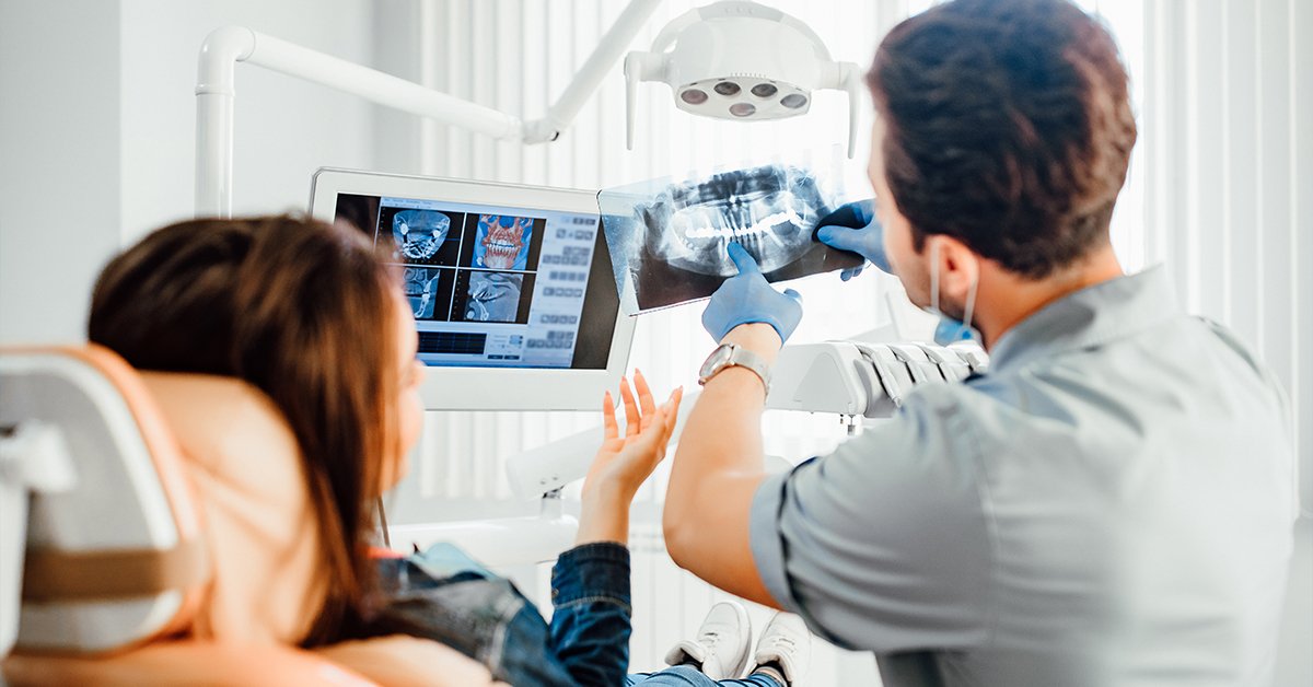 Dentist reviews mouth x-ray with patient